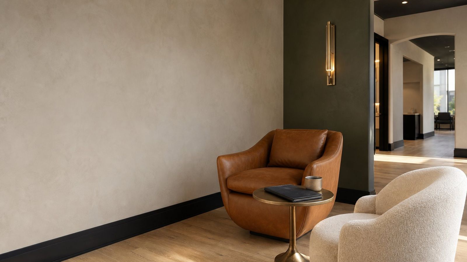 The Von Rae client waiting nook with cognac leather chair, boucle chair, and brass side table