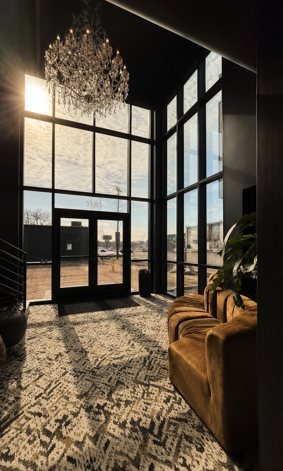 The Von Rae glass entry with crystal chandelier and cognac velvet sofa at sunset